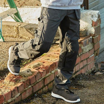 Person wearing dark gray work boots and pants on a construction site.