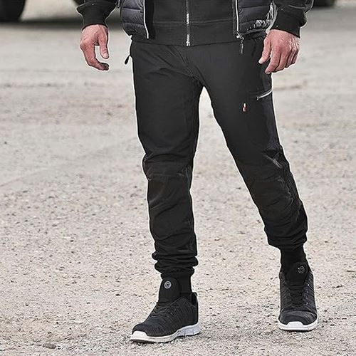 Person wearing black pants and black shoes on a gravel surface